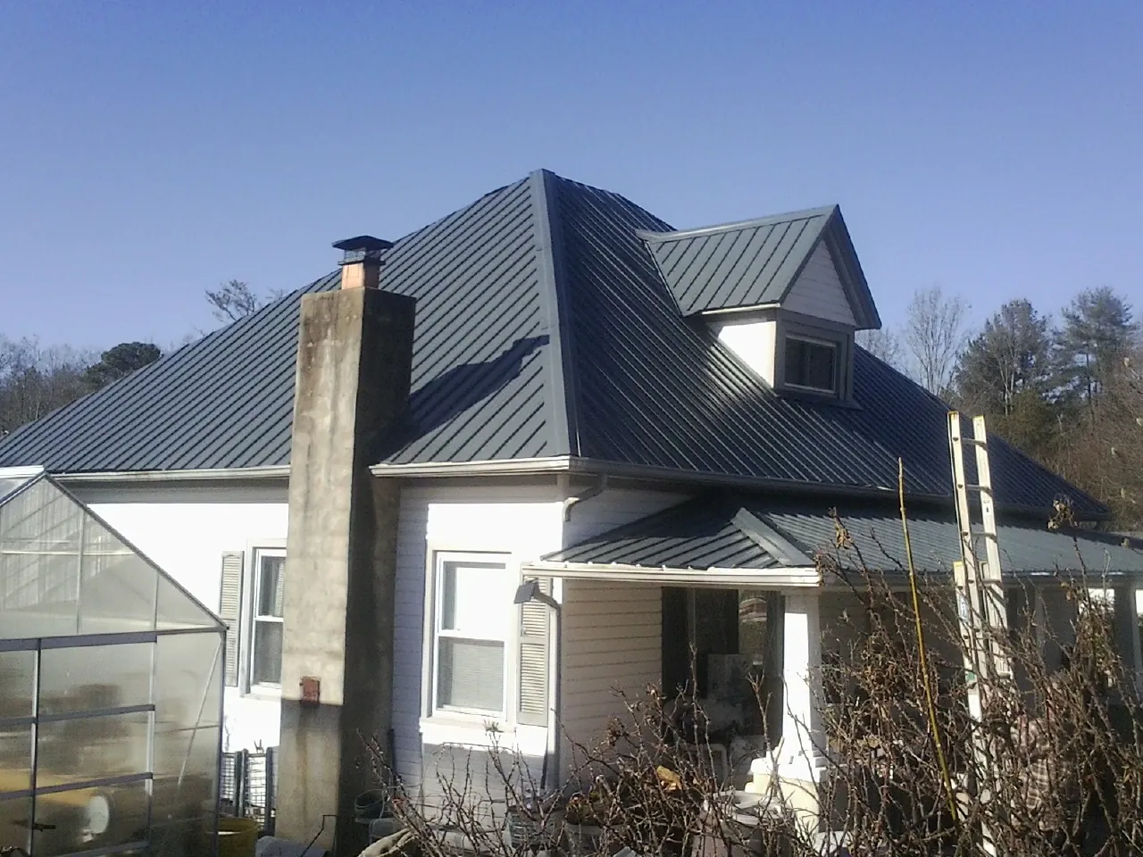 Dark blue standing seam metal roof on a white farmhouse with dormer — Slate & Tile Roof Repair by Roofing Brothers in Flemington