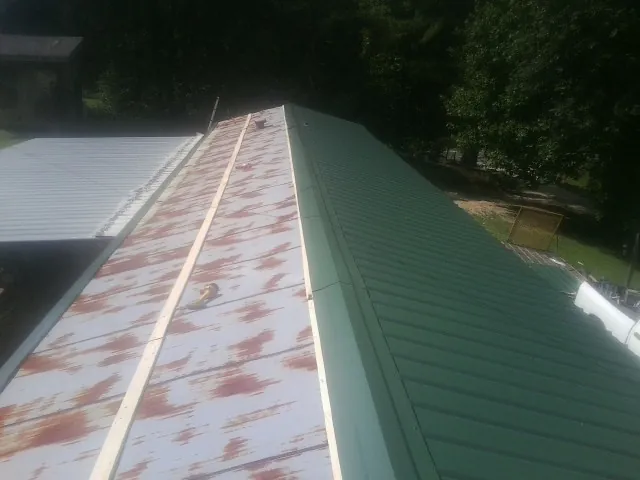 Old rusted panels beside newly installed green metal roofing — Wind Damage Roof Repair by Roofing Brothers in Flemington