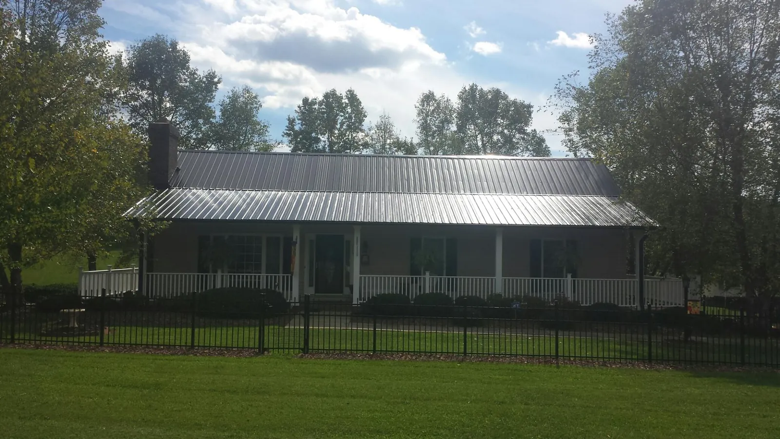 Gray metal roof on a brick ranch with a full width front porch — Gutter Guard Installation work by our crew in Flemington
